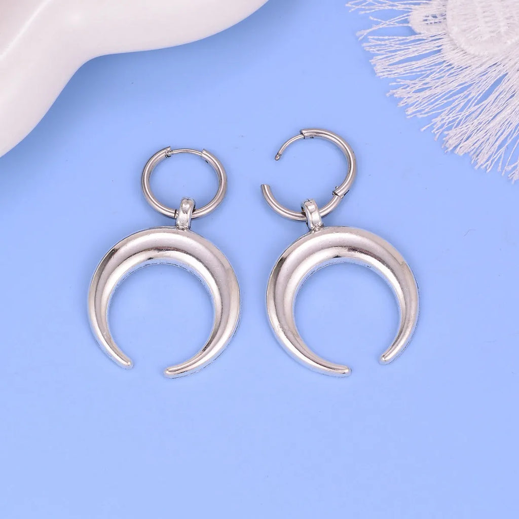 A pair of large silver geometric hoop earrings with a detailed Gothic moon motif, shown as clip-ons.