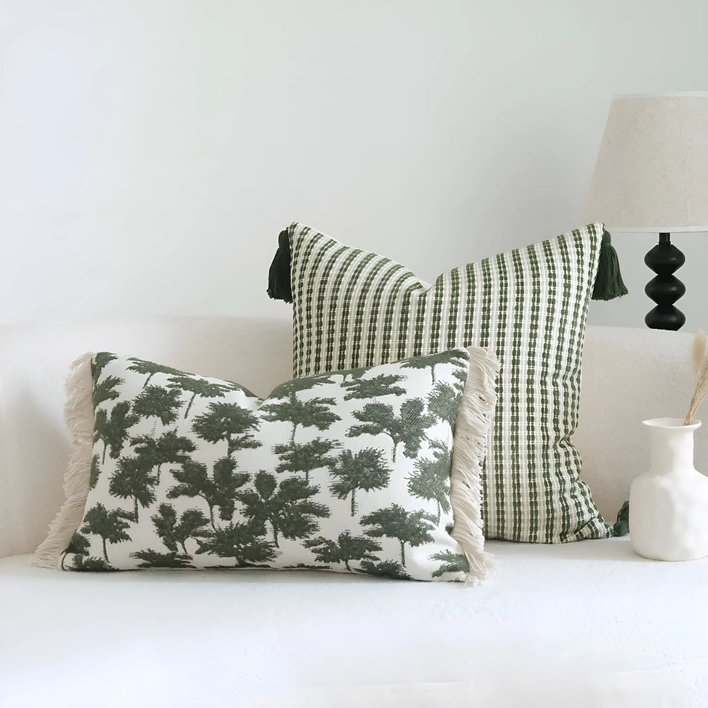 Green striped and botanical patterned hotel sample pillow with tassels on a bed display.