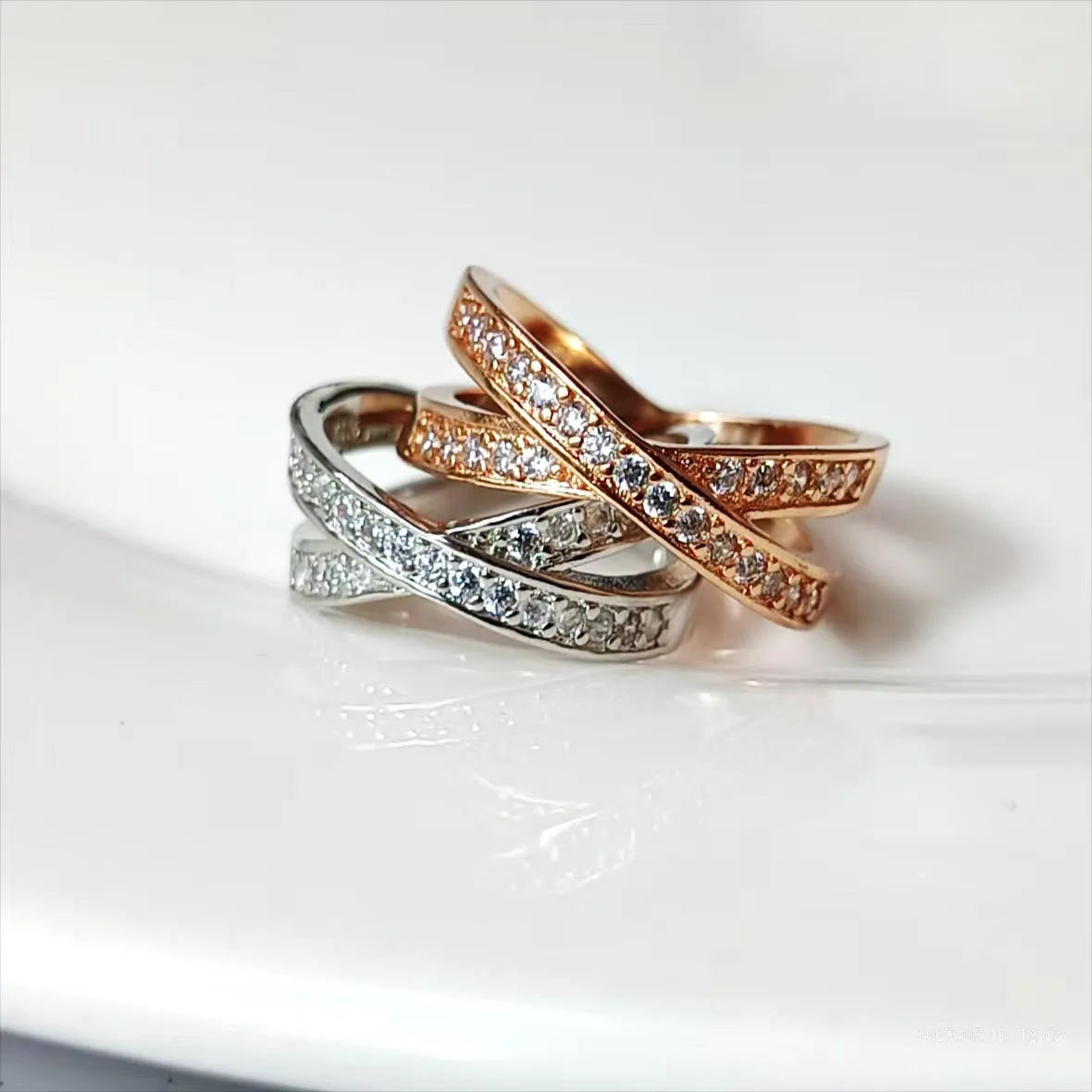 Geometric cross design ring with micro-inlaid zircon on a copper band, shown in silver and rose gold finishes.