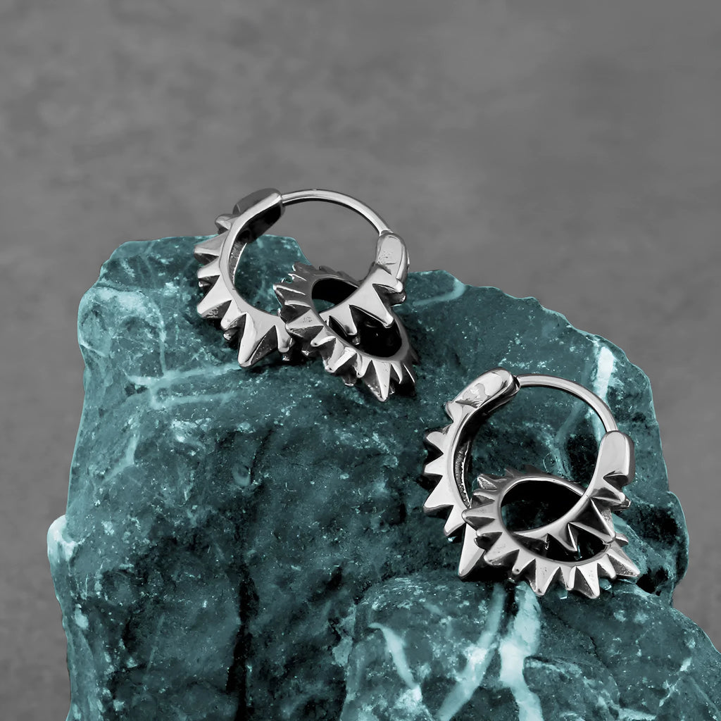 A pair of polished stainless steel round ring earrings in a steel colour finish on a plain background.