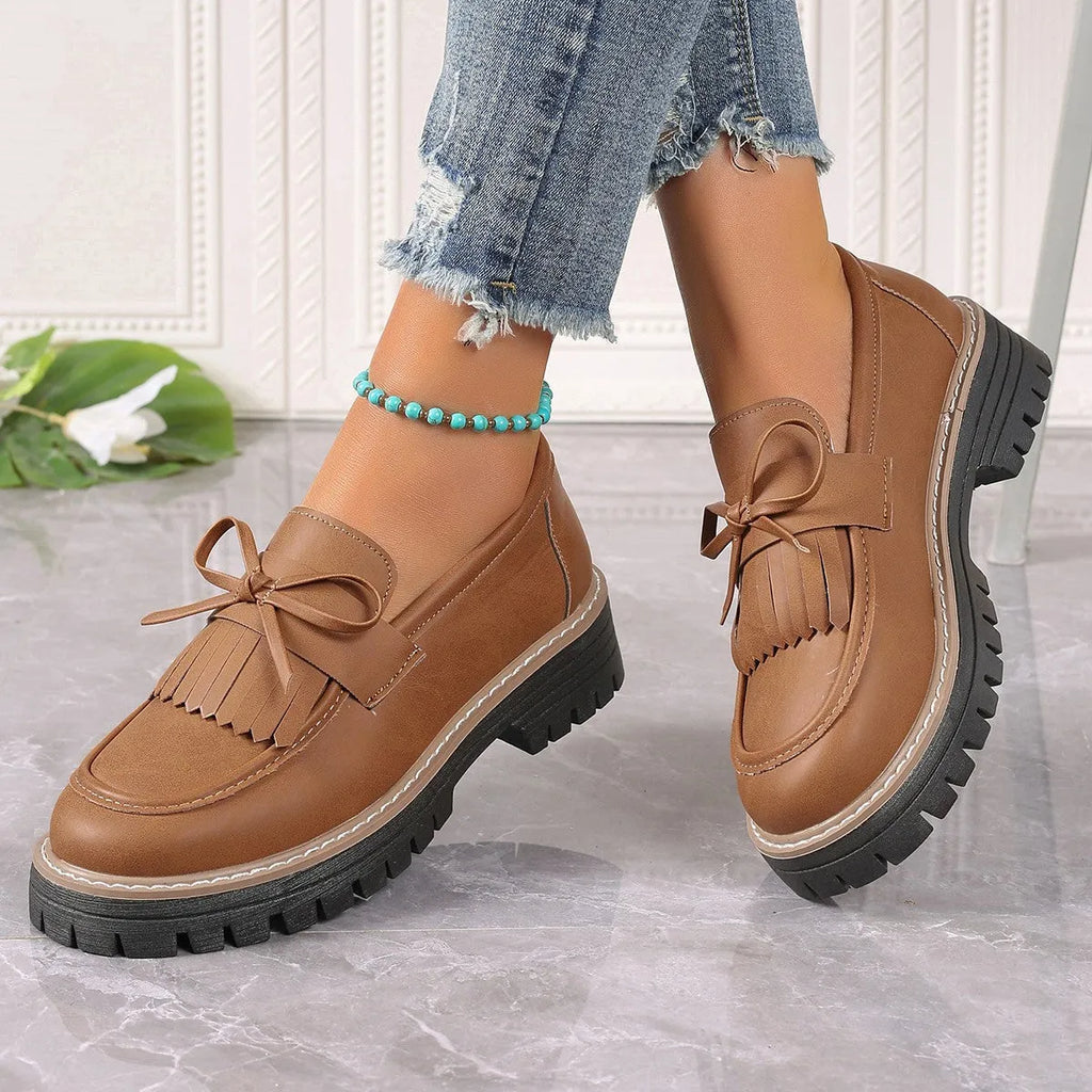 Women's black plus size loafers with a tassel and bowknot decoration and a chunky rubber sole.