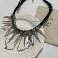 Leather necklace with round beads, a tassel, and silver rivet details on a white background.