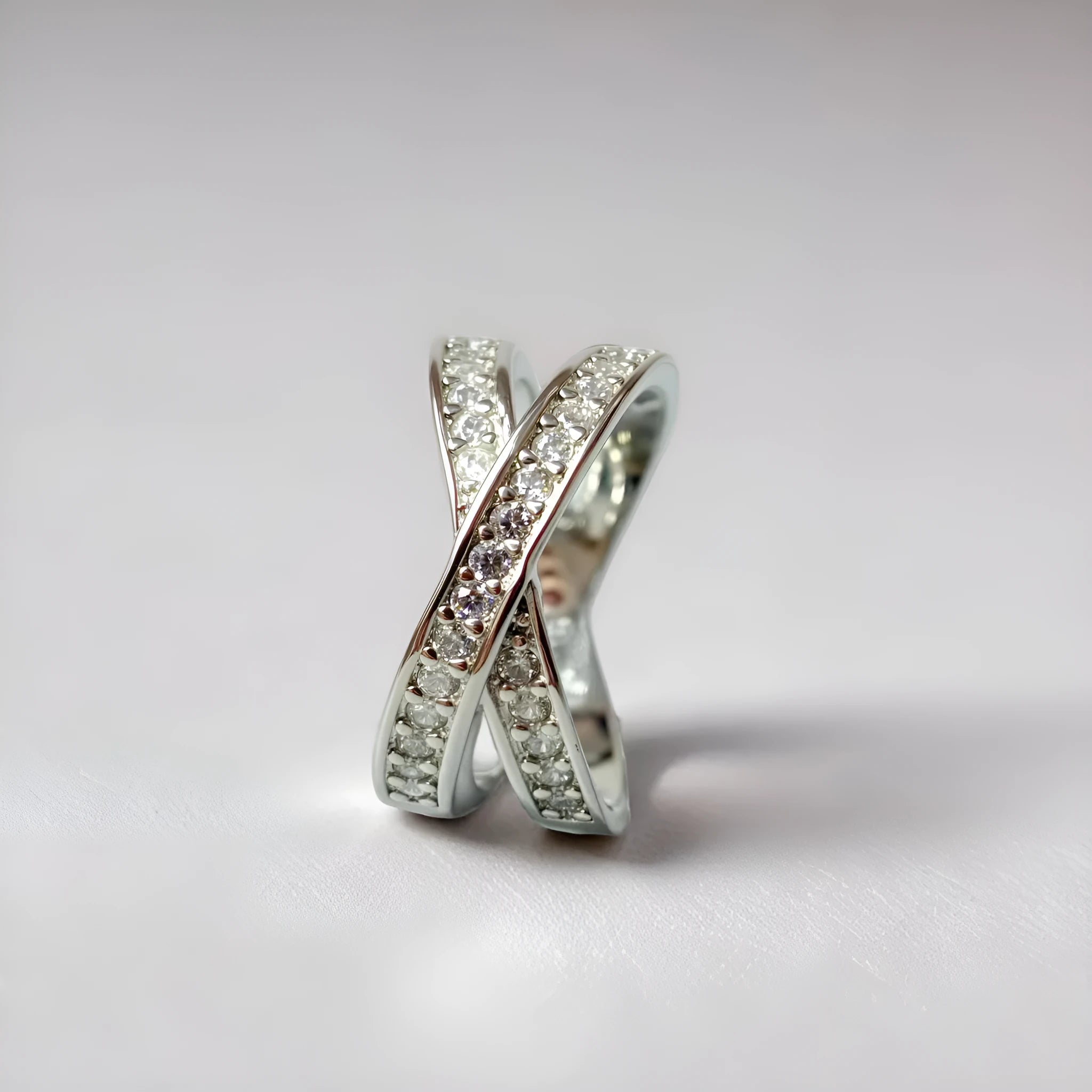 Geometric cross design ring with micro-inlaid zircon on a copper band, shown in silver and rose gold finishes.