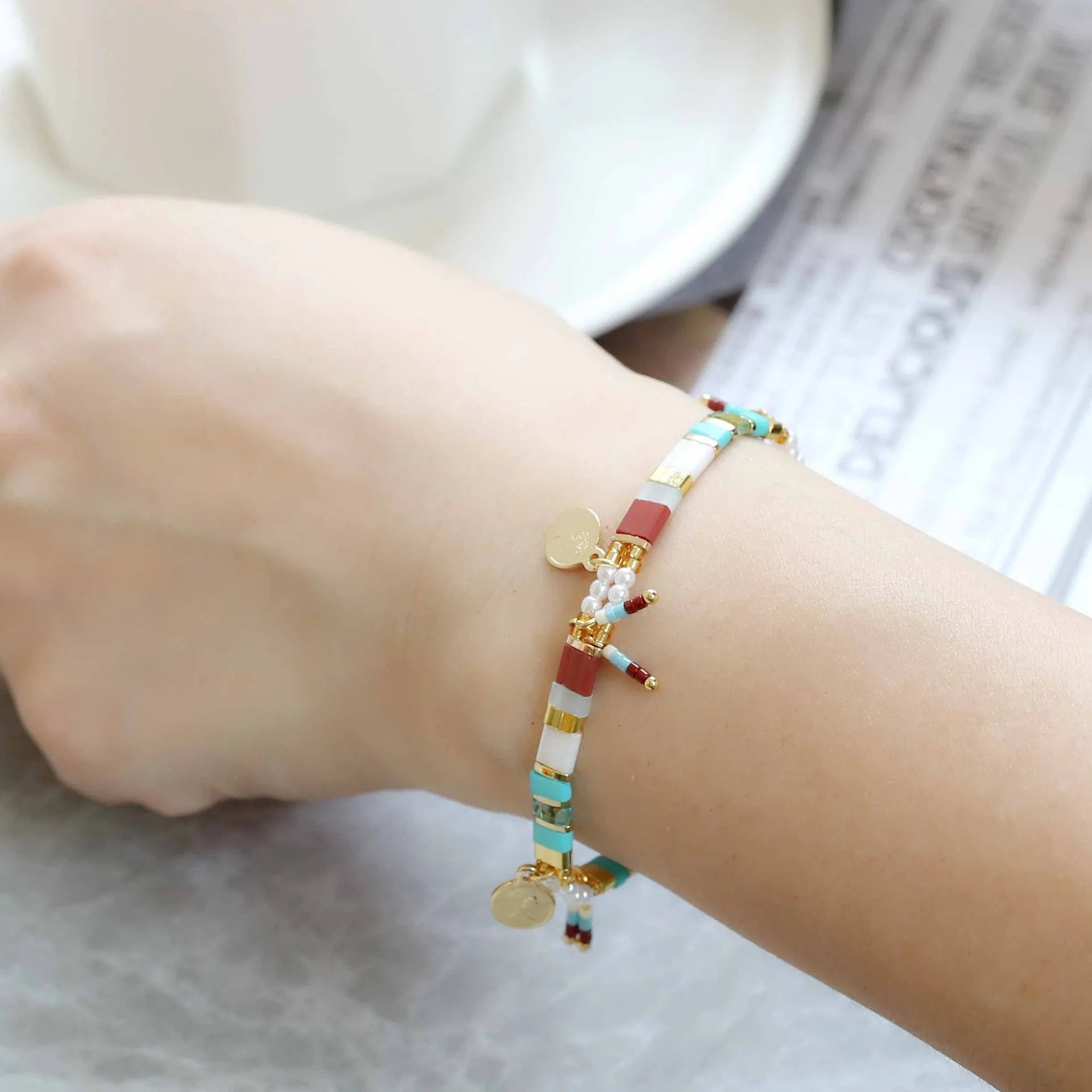 Women's bracelet with imitation pearl and coloured glass beads on wrist, showing adjustable clasp.