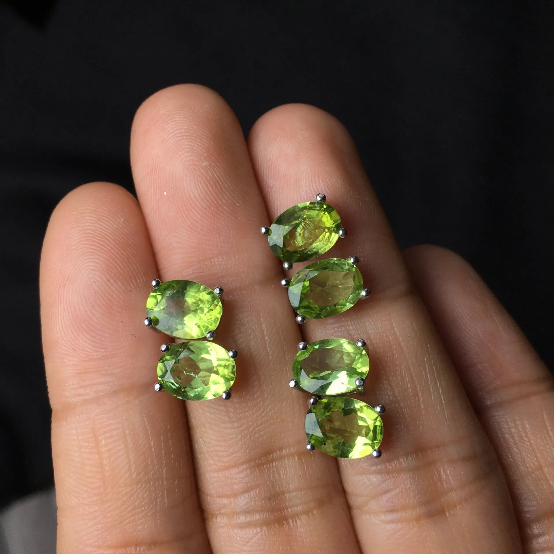 Close-up of grass green natural olivine stud earrings in S925 silver, showing ellipse-shaped stone.