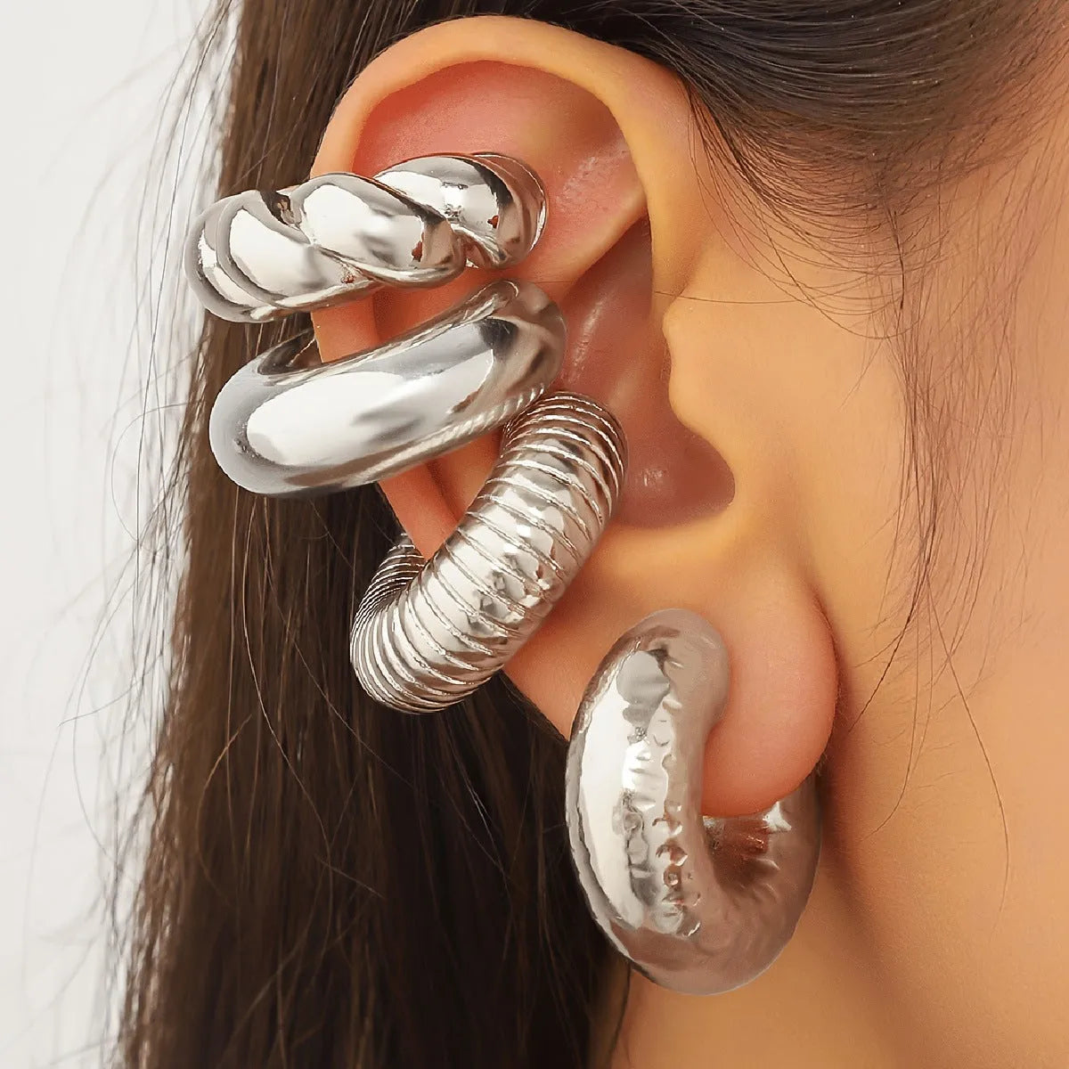 Set of four geometric gold and silver clip-on earrings for women on a flat surface.