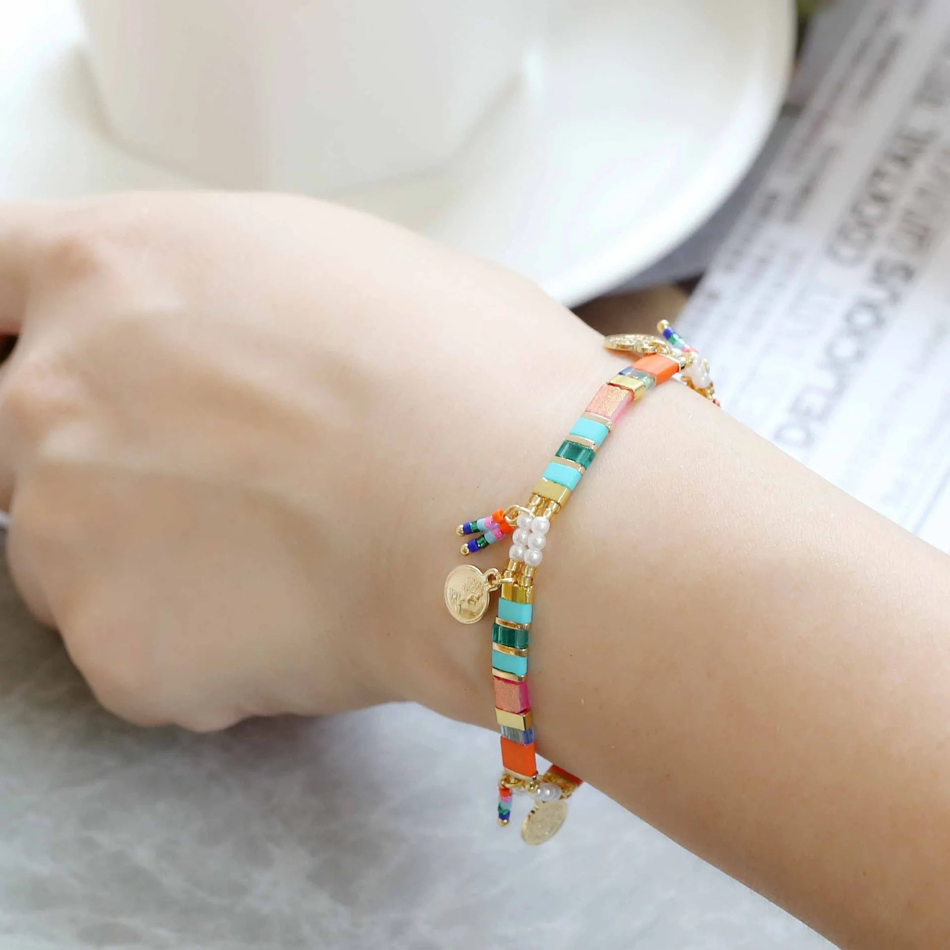Women's bracelet with imitation pearl and coloured glass beads on wrist, showing adjustable clasp.