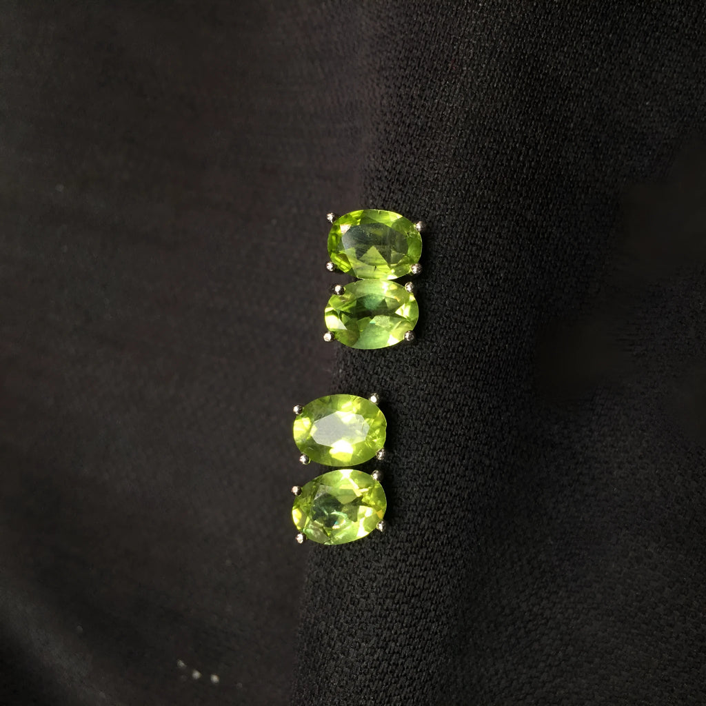 Close-up of grass green natural olivine stud earrings in S925 silver, showing ellipse-shaped stone.
