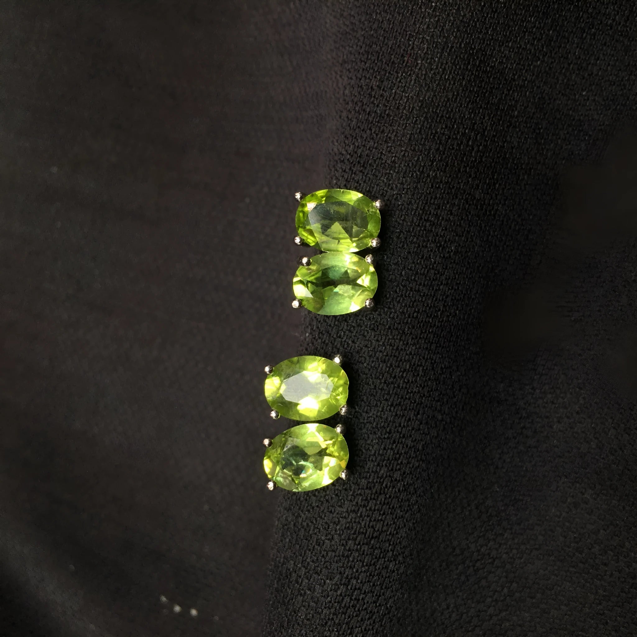 Close-up of grass green natural olivine stud earrings in S925 silver, showing ellipse-shaped stone.