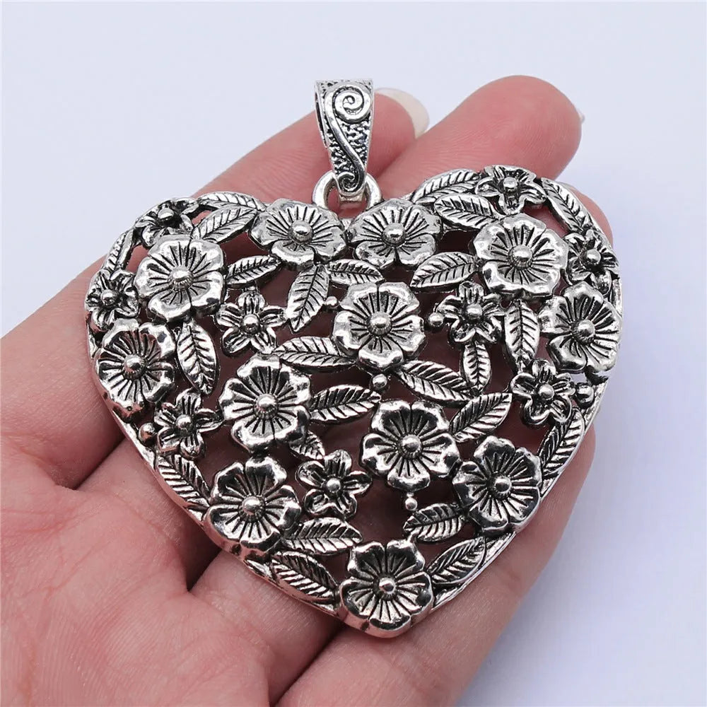 Close-up of a hollow flower love pendant in ancient silver colour, showing its detailed openwork design.
