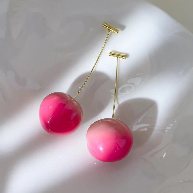 A pair of women's acrylic earrings shaped like juicy peaches on copper findings.