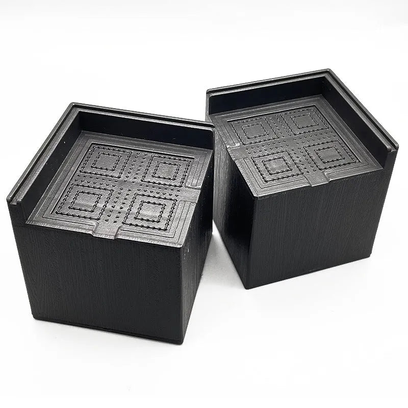 Four black plastic furniture foot mats for raising bed or sofa legs on hard floors.