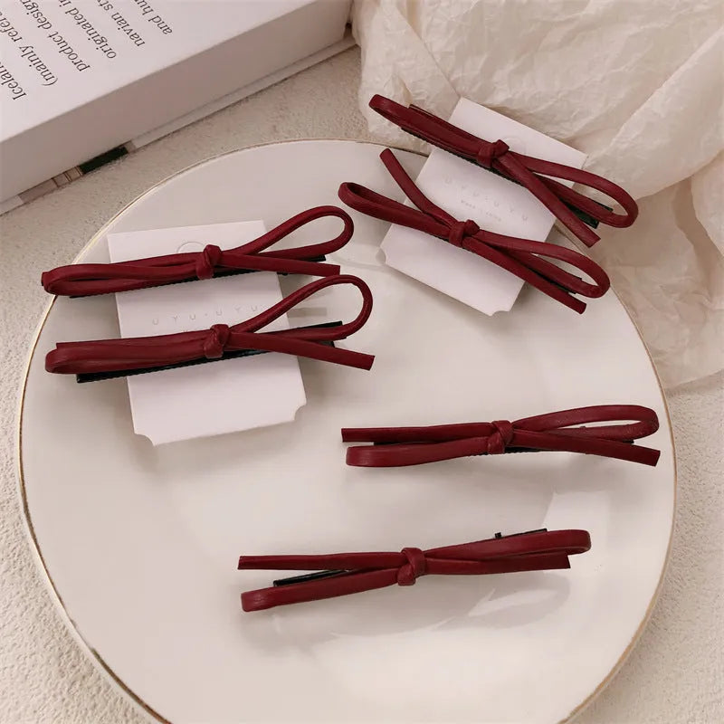 Wine red leather bow hair barrette on a white background.