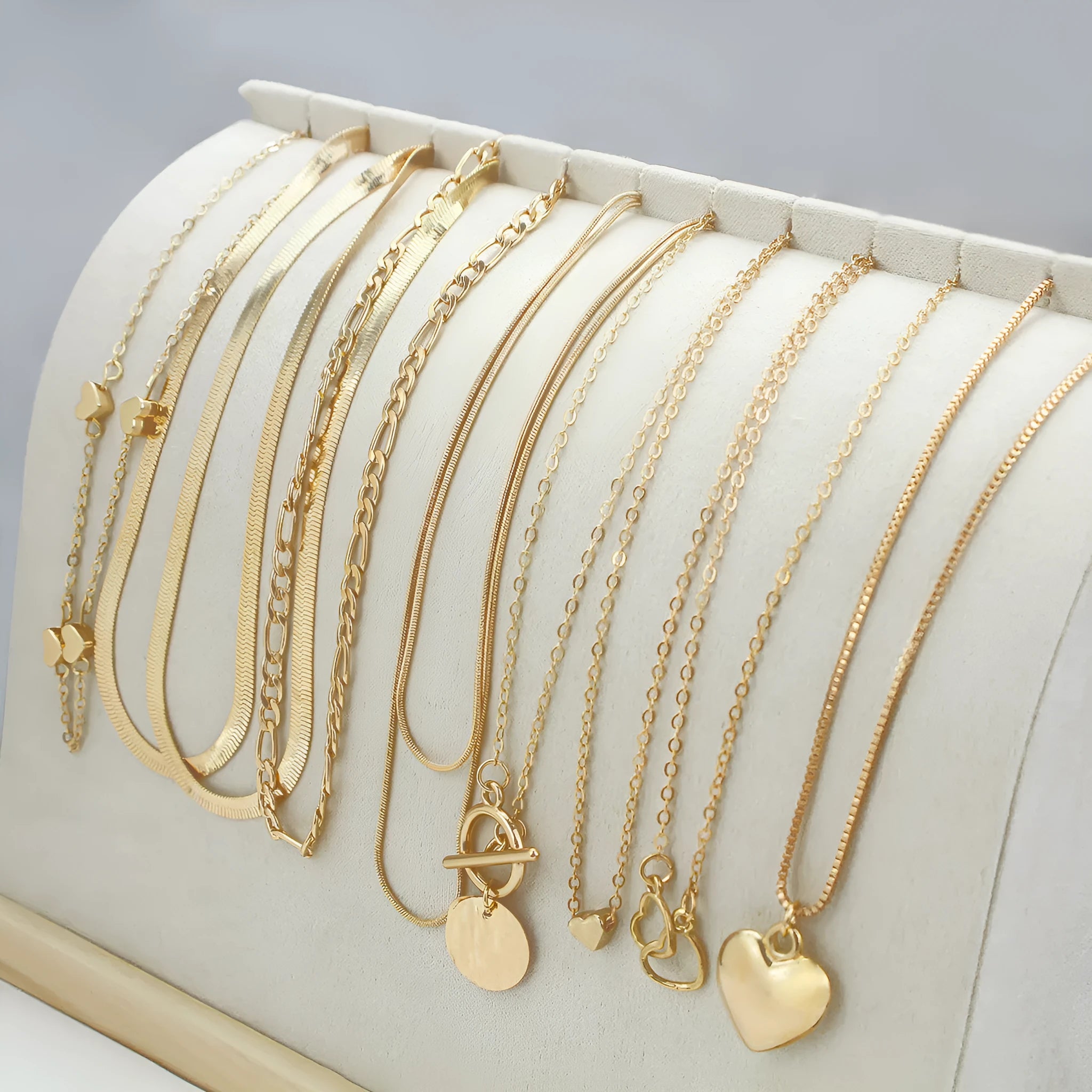 Set of 10 gold women's necklaces with adjustable chains and alloy pendants displayed in gift packaging