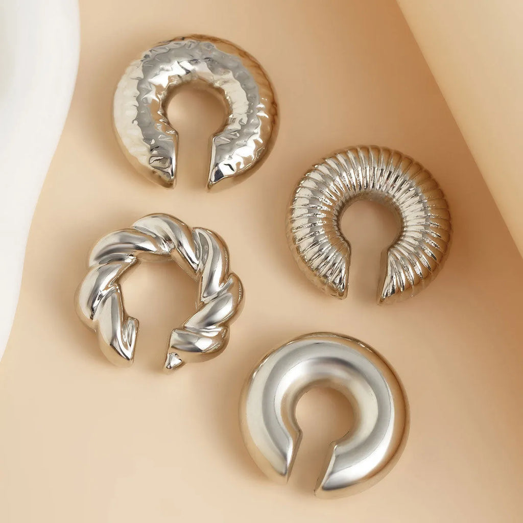 Set of four geometric gold and silver clip-on earrings for women on a flat surface.
