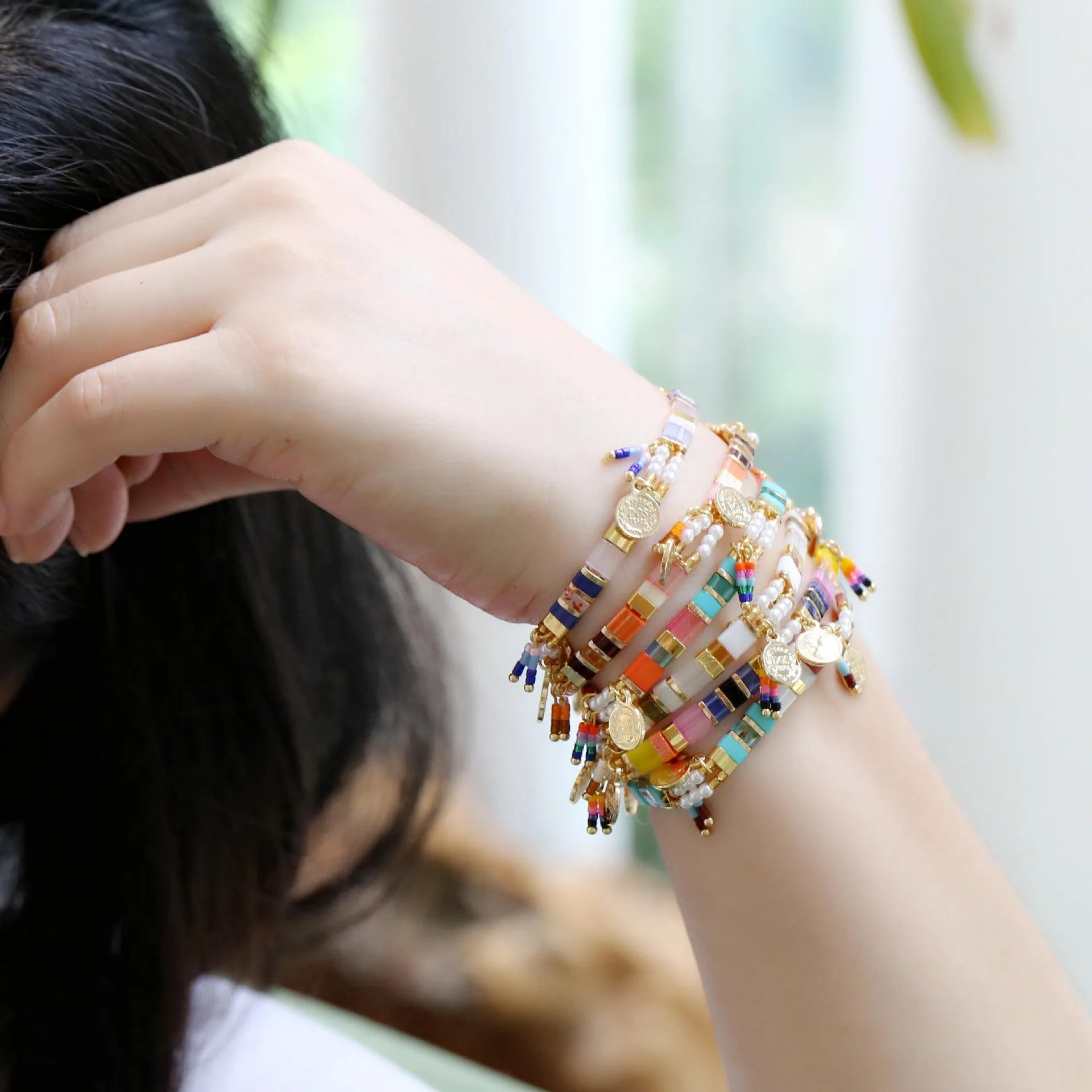 Women's bracelet with imitation pearl and coloured glass beads on wrist, showing adjustable clasp.