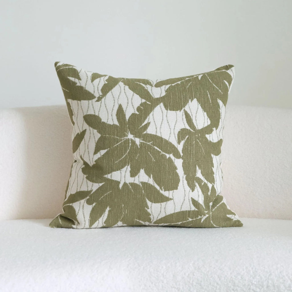Green striped and botanical patterned hotel sample pillow with tassels on a bed display.