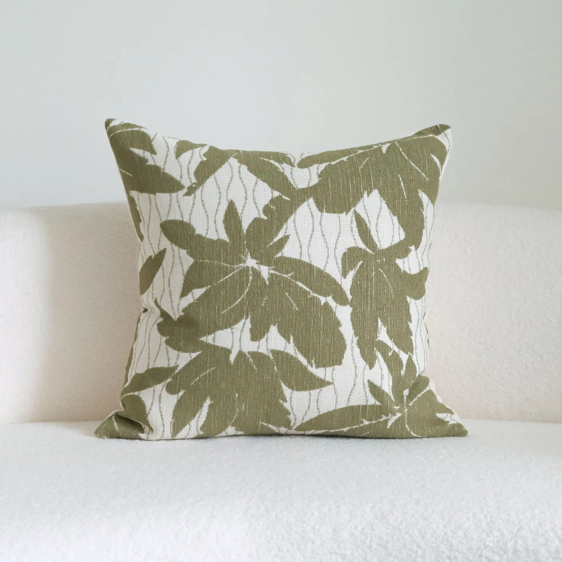 Green striped and botanical patterned hotel sample pillow with tassels on a bed display.