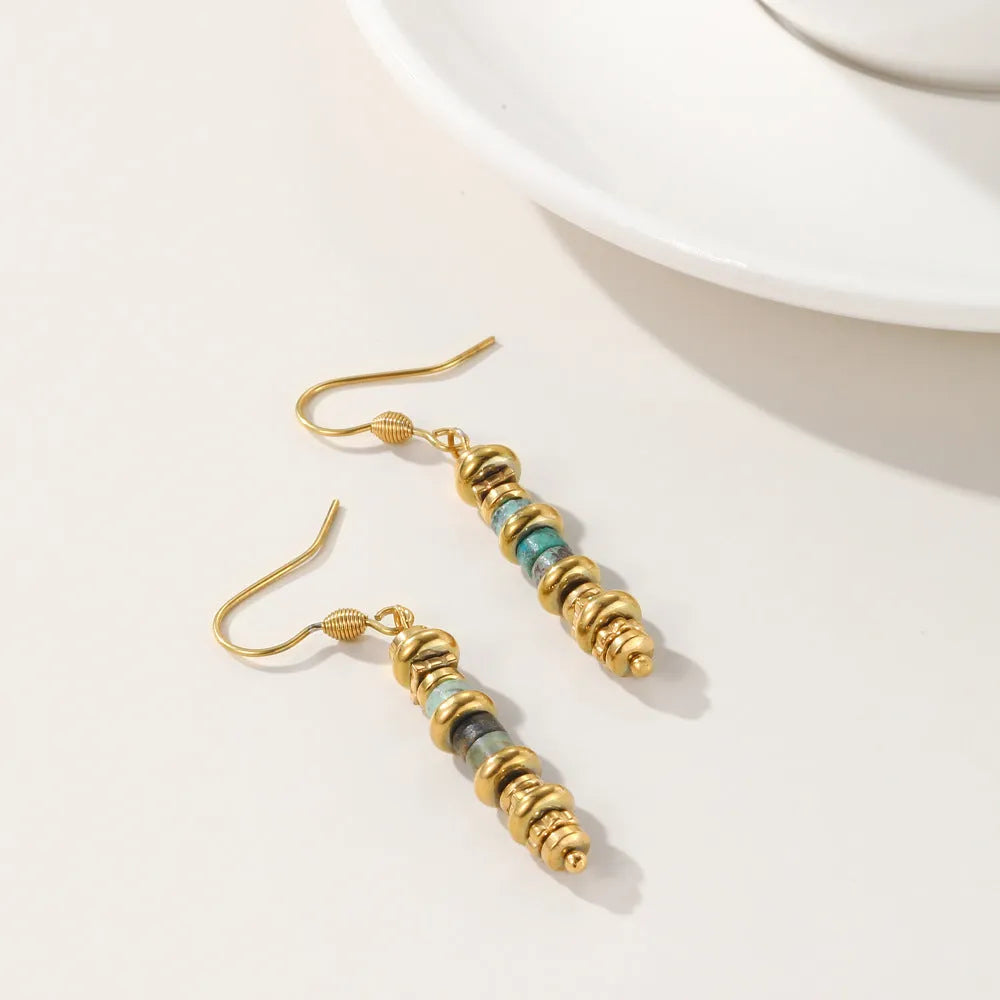 A pair of geometric-shaped, gold-coloured titanium steel dangle earrings on a white background.
