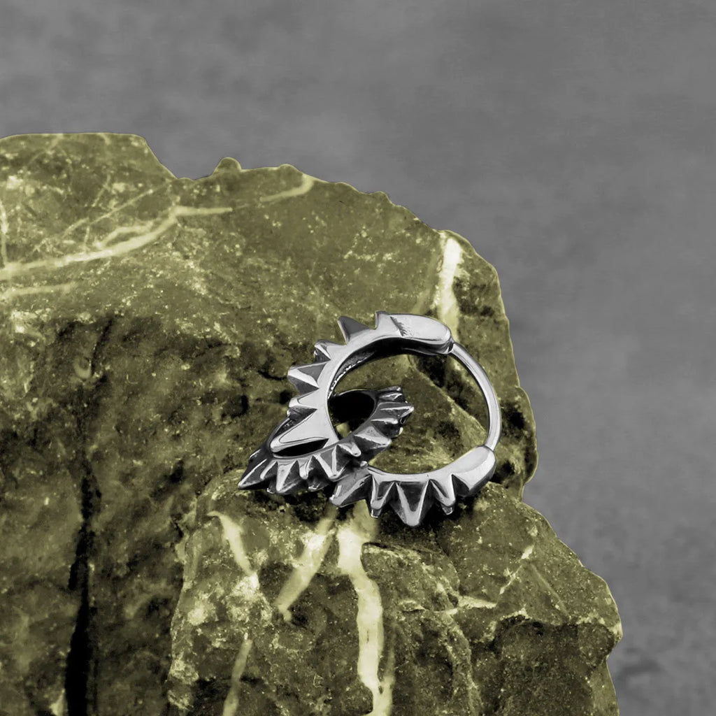 A pair of polished stainless steel round ring earrings in a steel colour finish on a plain background.