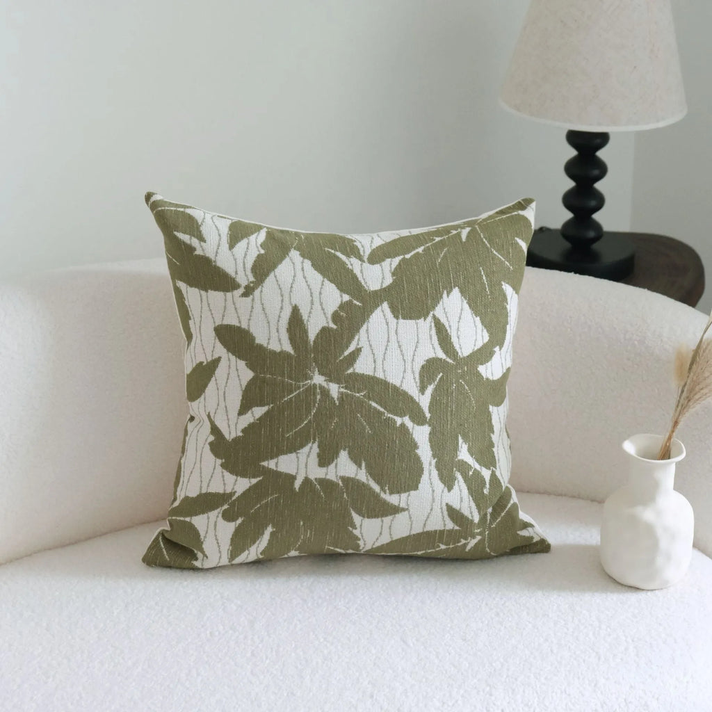Green striped and botanical patterned hotel sample pillow with tassels on a bed display.