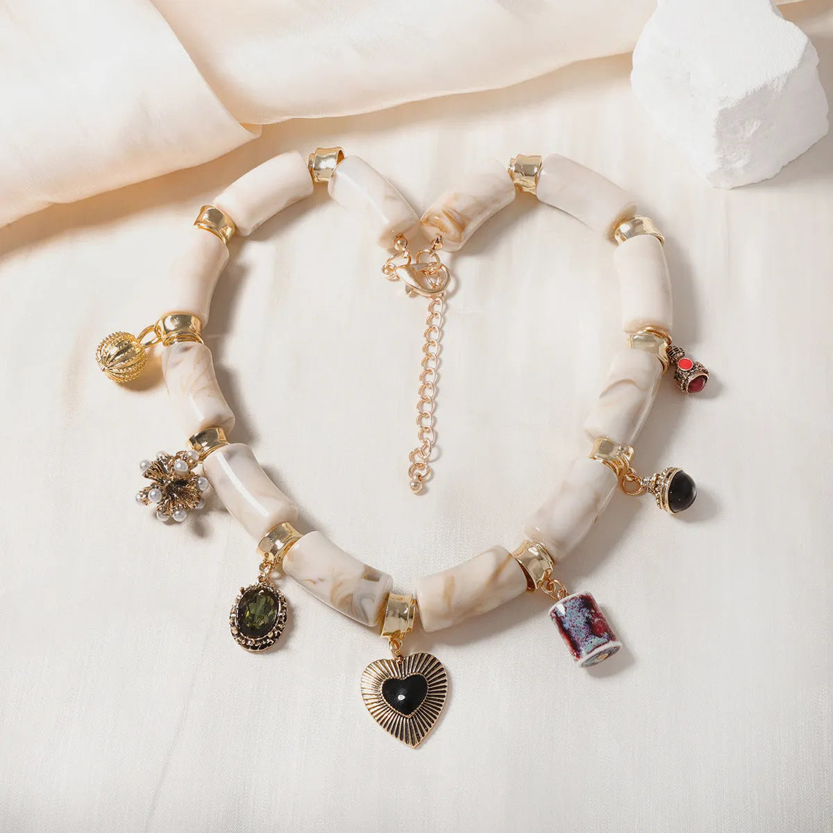 Close-up of a women's resin necklace with a heart-shaped pendant containing a bamboo detail and an electroplated metallic finish.