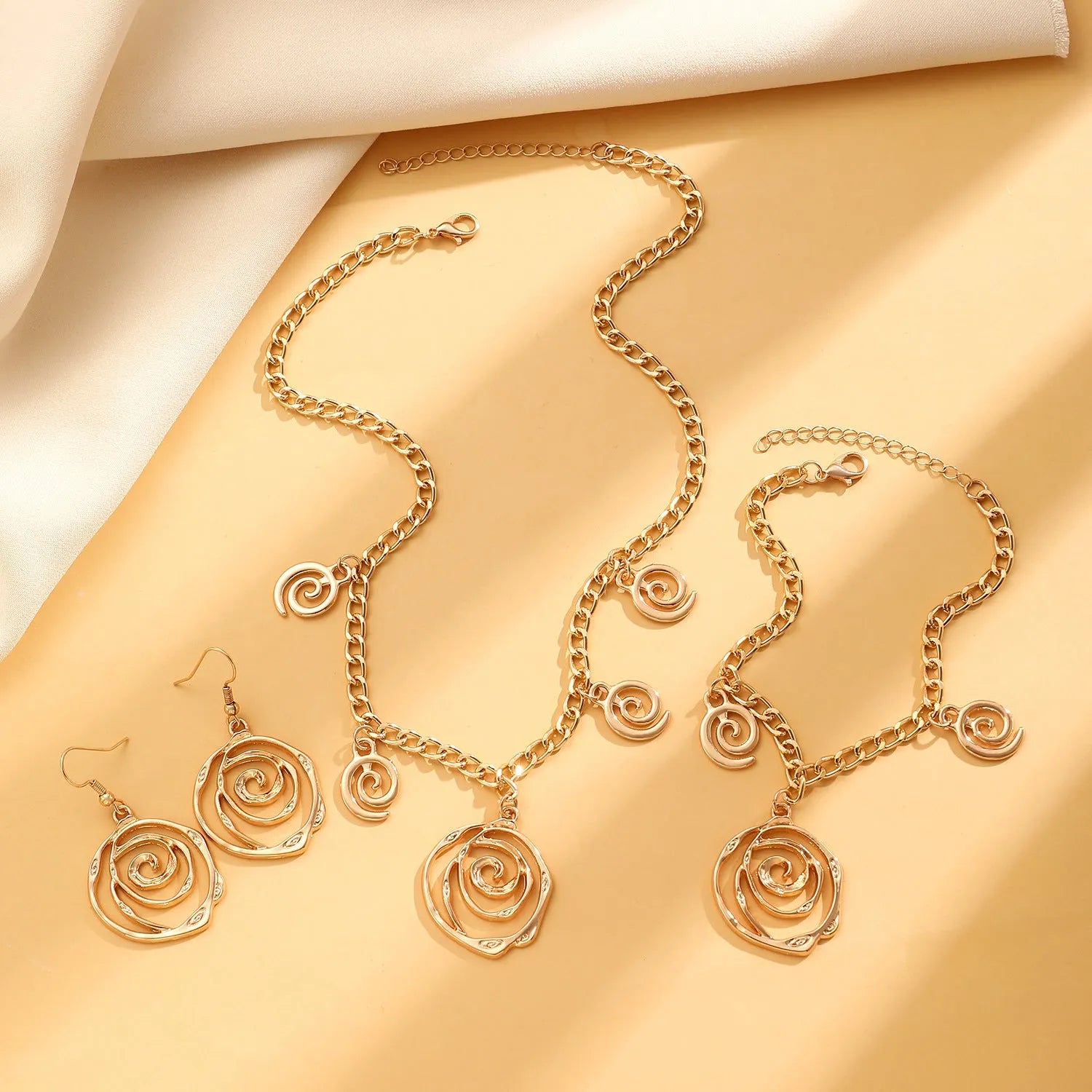 Spiral donut jewellery set showing necklace, bracelet and ear hooks in gold or silver geometric circle design