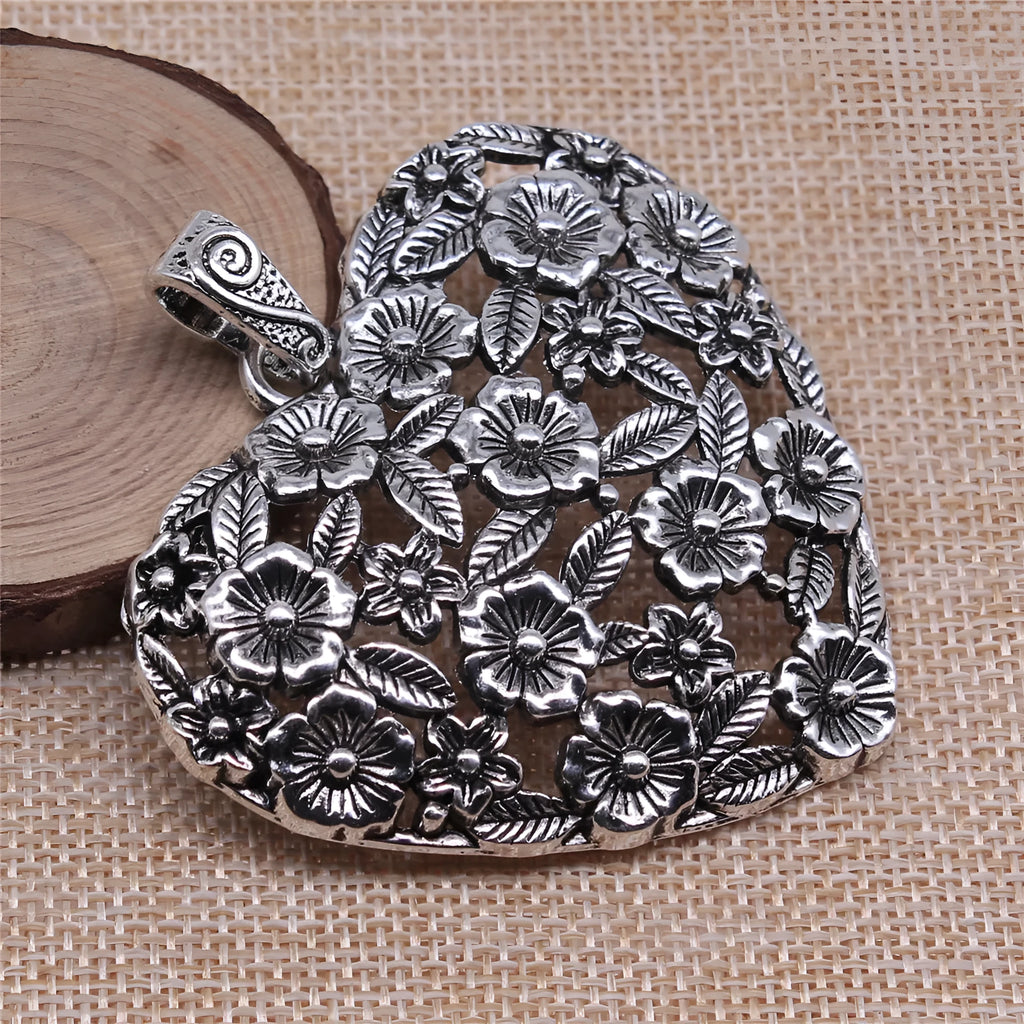 Close-up of a hollow flower love pendant in ancient silver colour, showing its detailed openwork design.