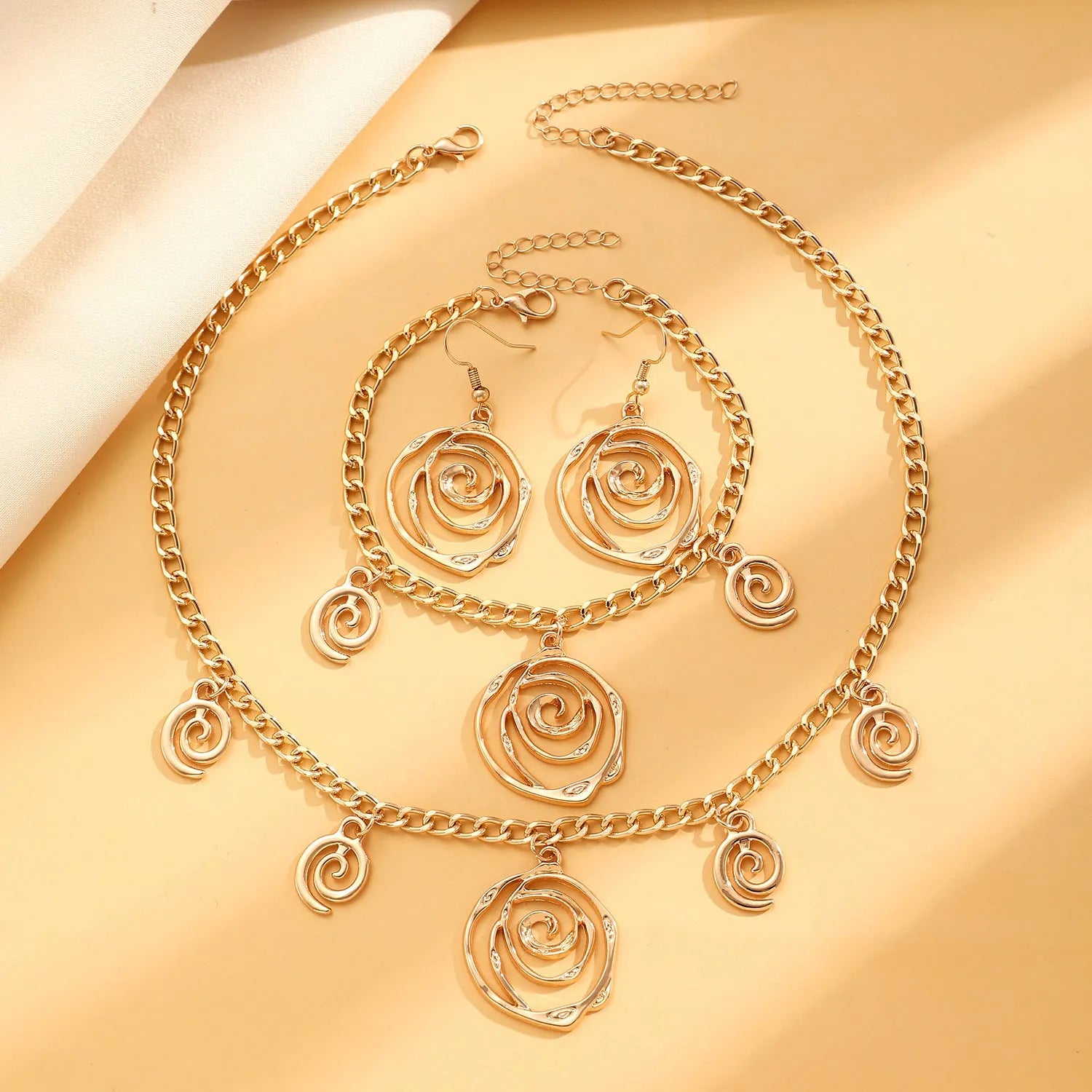 Spiral donut jewellery set showing necklace, bracelet and ear hooks in gold or silver geometric circle design
