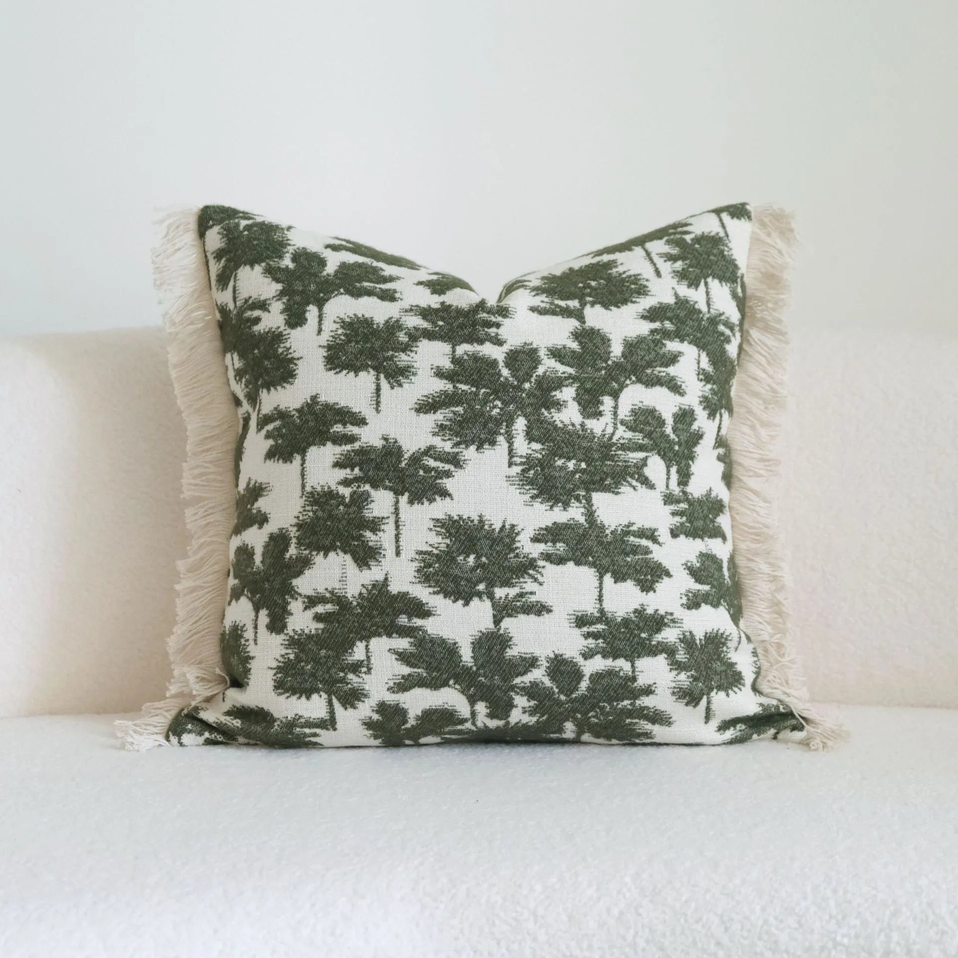 Green striped and botanical patterned hotel sample pillow with tassels on a bed display.