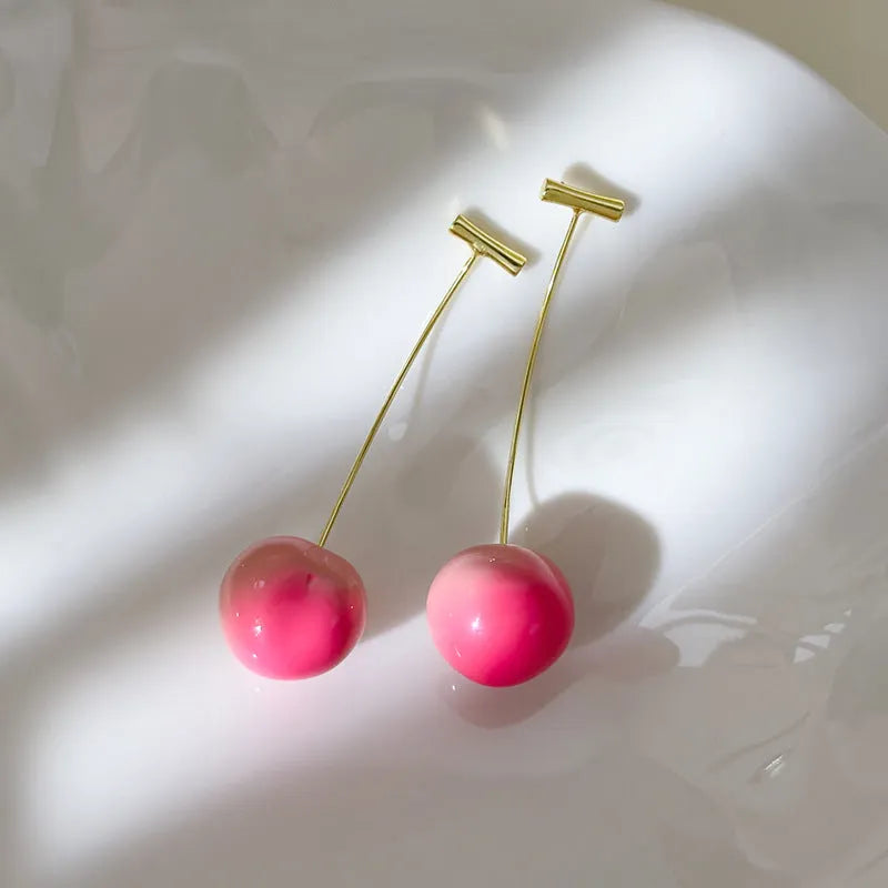 A pair of women's acrylic earrings shaped like juicy peaches on copper findings.