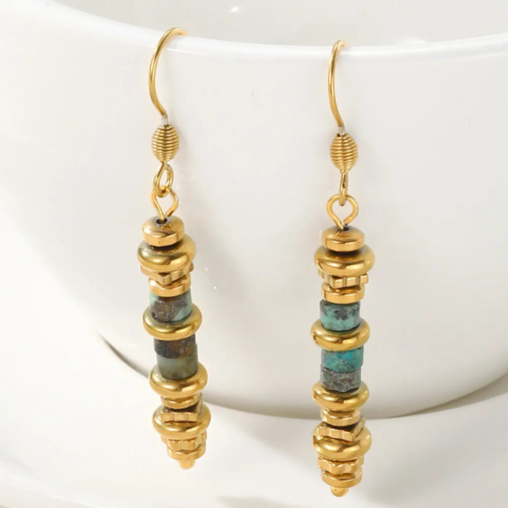 A pair of geometric-shaped, gold-coloured titanium steel dangle earrings on a white background.