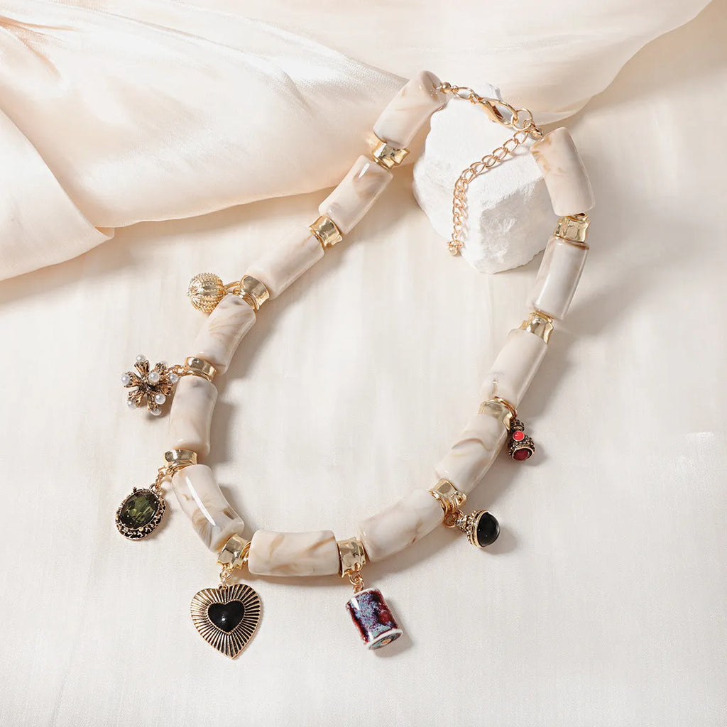 Close-up of a women's resin necklace with a heart-shaped pendant containing a bamboo detail and an electroplated metallic finish.