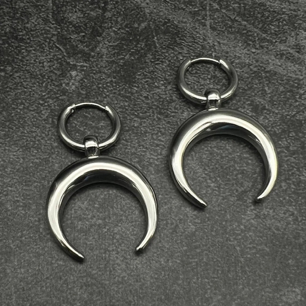 A pair of large silver geometric hoop earrings with a detailed Gothic moon motif, shown as clip-ons.