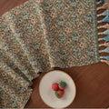 Nordic jacquard table runner with tassel trim in dark blue striped pattern laid on a wooden table.