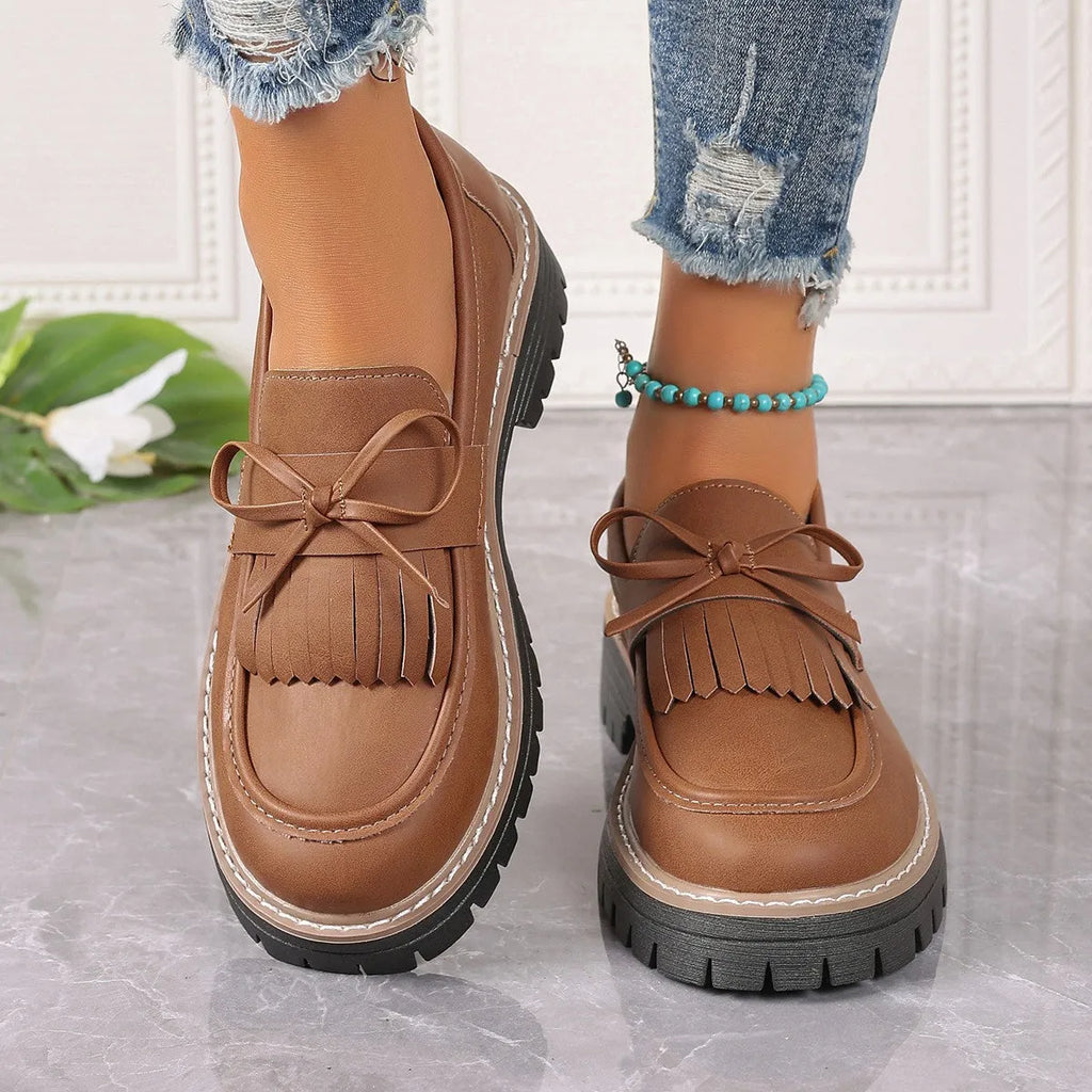 Women's black plus size loafers with a tassel and bowknot decoration and a chunky rubber sole.