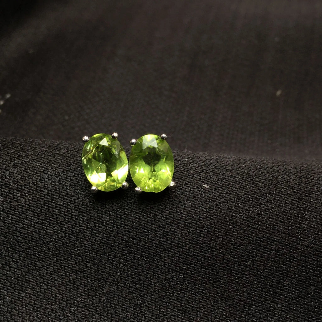Close-up of grass green natural olivine stud earrings in S925 silver, showing ellipse-shaped stone.