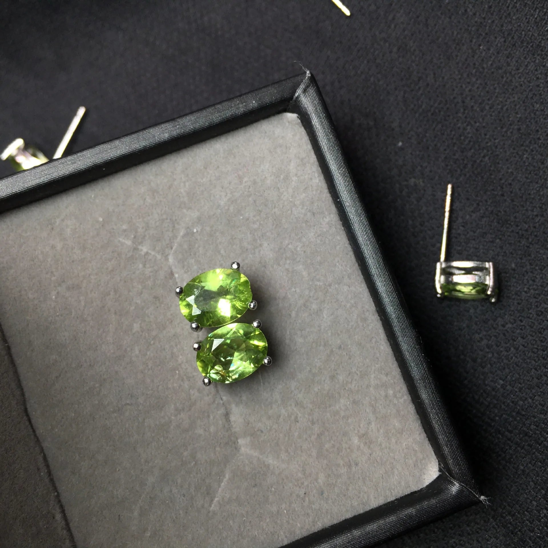 Close-up of grass green natural olivine stud earrings in S925 silver, showing ellipse-shaped stone.