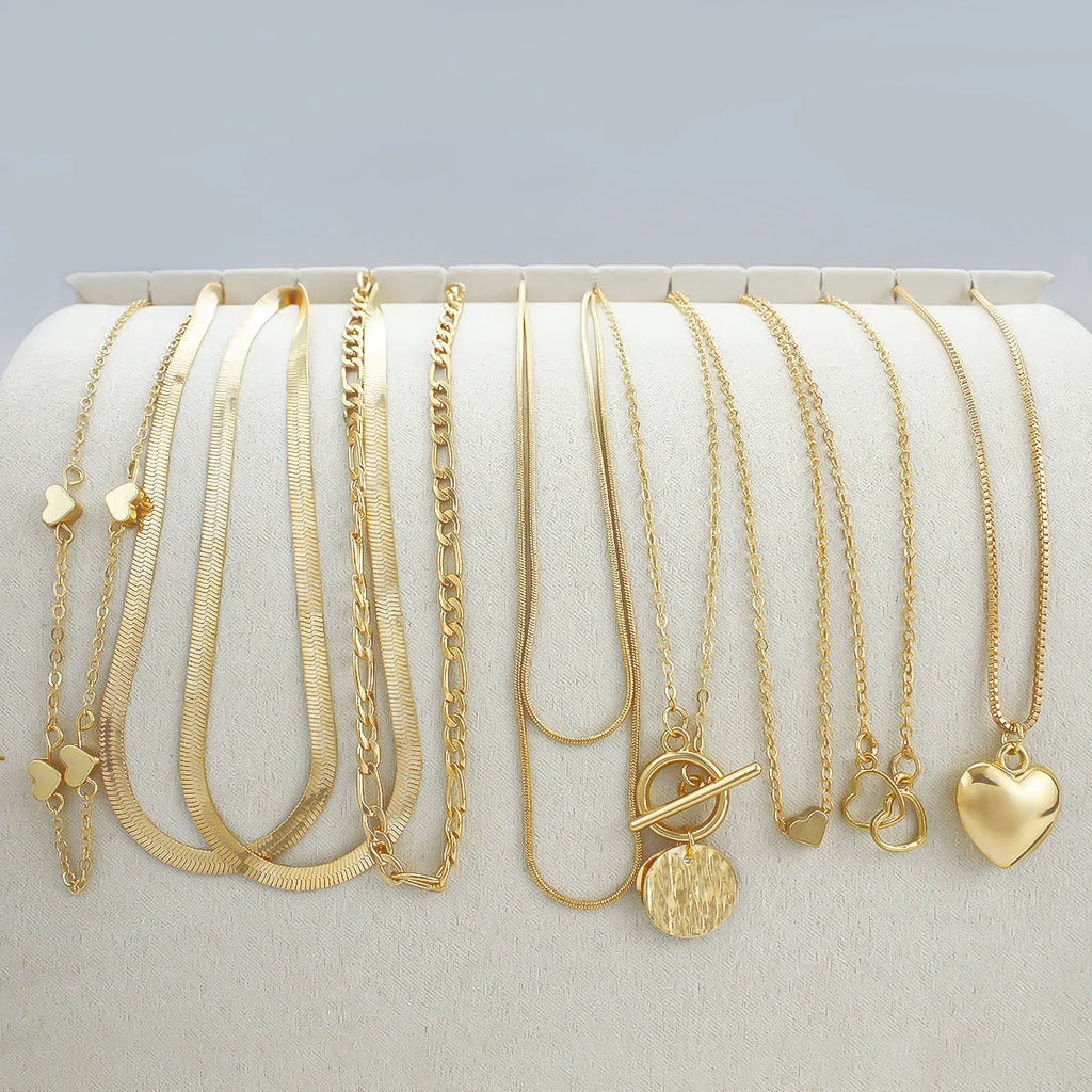 Set of 10 gold women's necklaces with adjustable chains and alloy pendants displayed in gift packaging