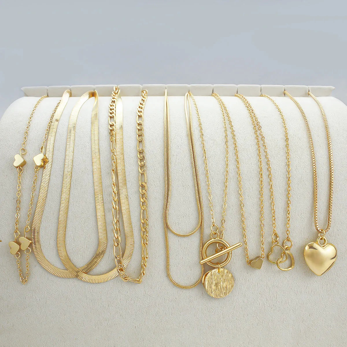 Set of 10 gold women's necklaces with adjustable chains and alloy pendants displayed in gift packaging