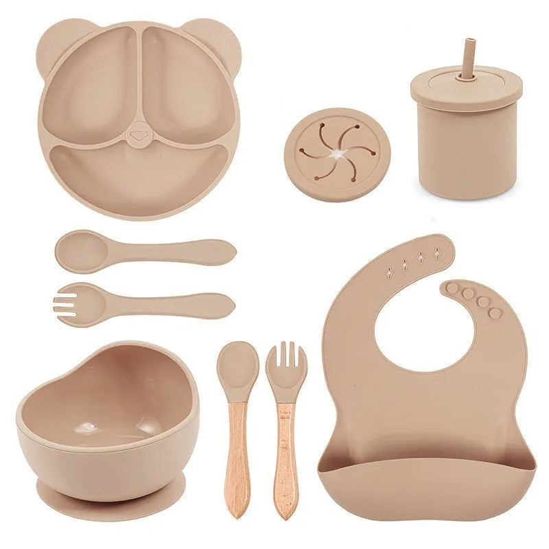 Children's silicone tableware set with cat ear cup in beige, blue and other colours on a table