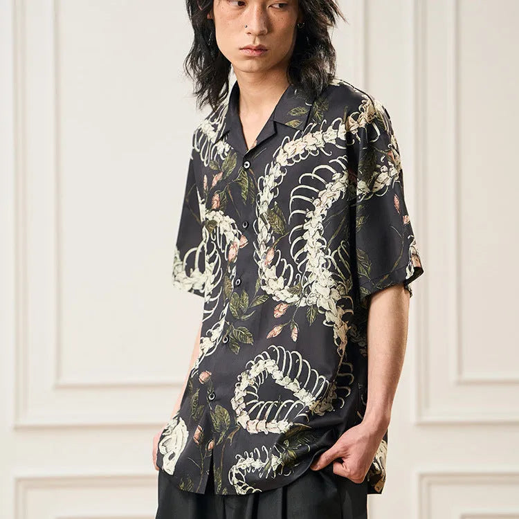 Man wearing a loose fit Cuban collar shirt with a printed snake bone and floral pattern in a summer setting.