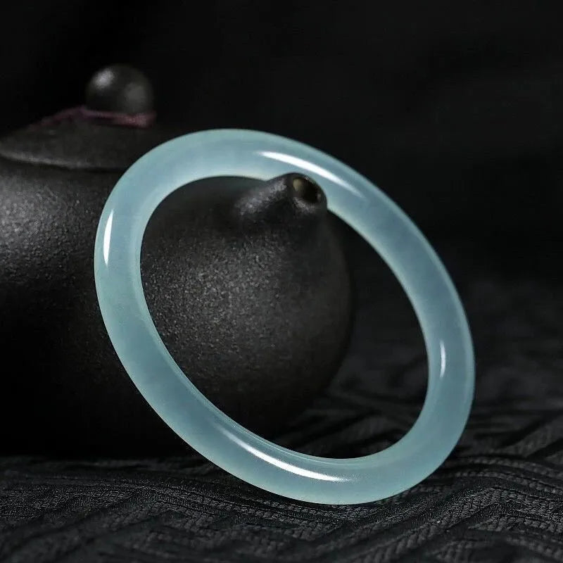 Jade bracelet with carved floating flower and auspicious cloud pattern in emerald green.