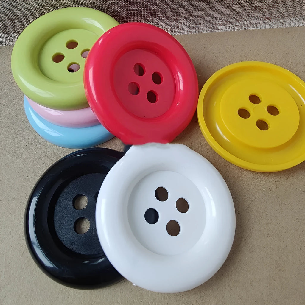 Assortment of oversized round plastic buttons in multiple colours with four stitching holes.