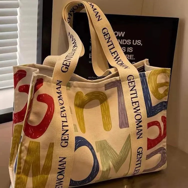 Large canvas tote bag with printed design, featuring two fabric handles, shown in available colour style options.