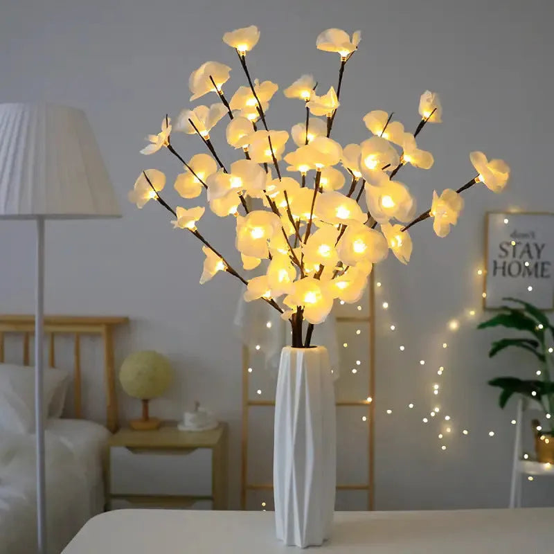 Pink artificial Phalaenopsis orchid branch LED decorative light, 65cm tall, on a bedside table.