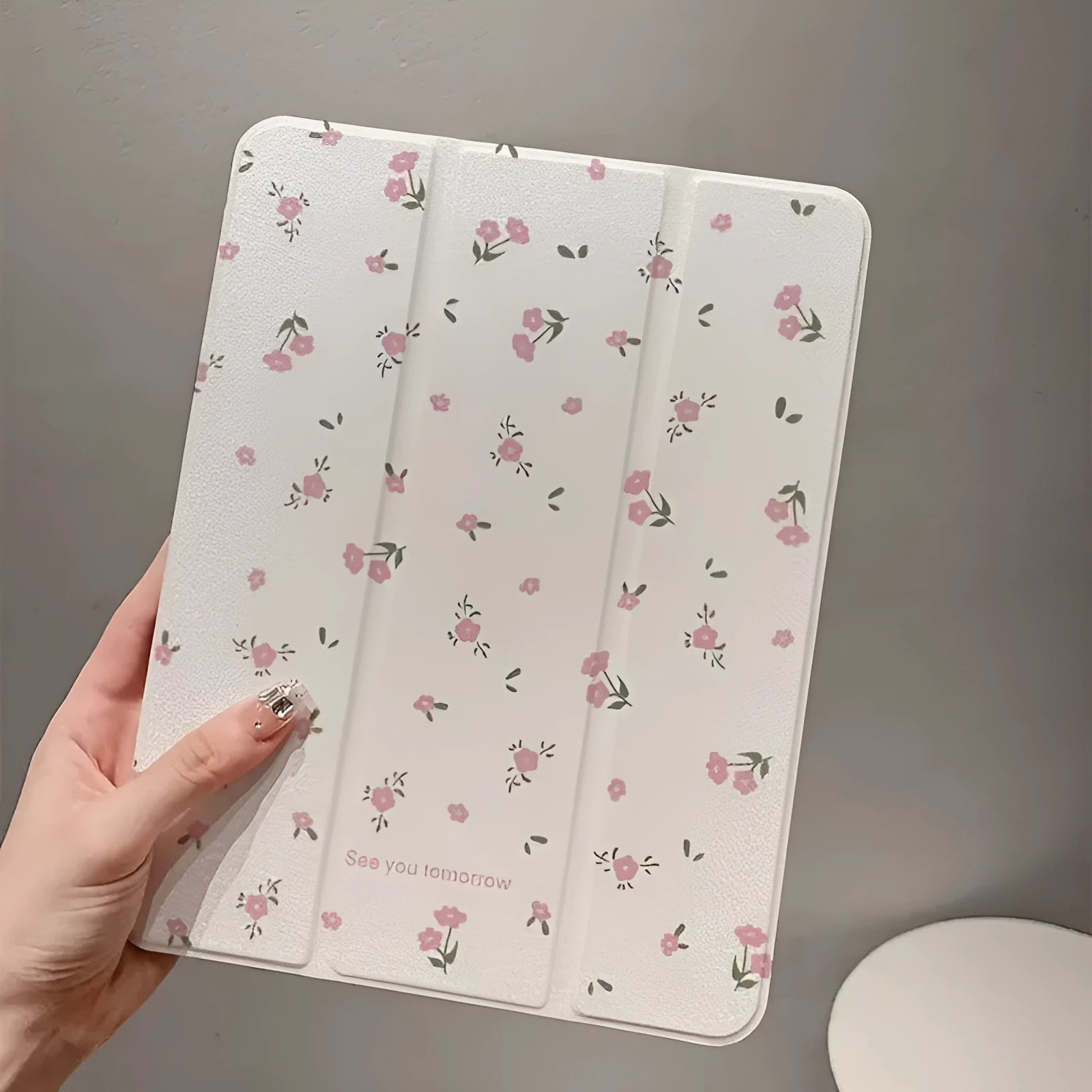 Clear iPad case with floral cartoon pattern, shown folded into a stand position.