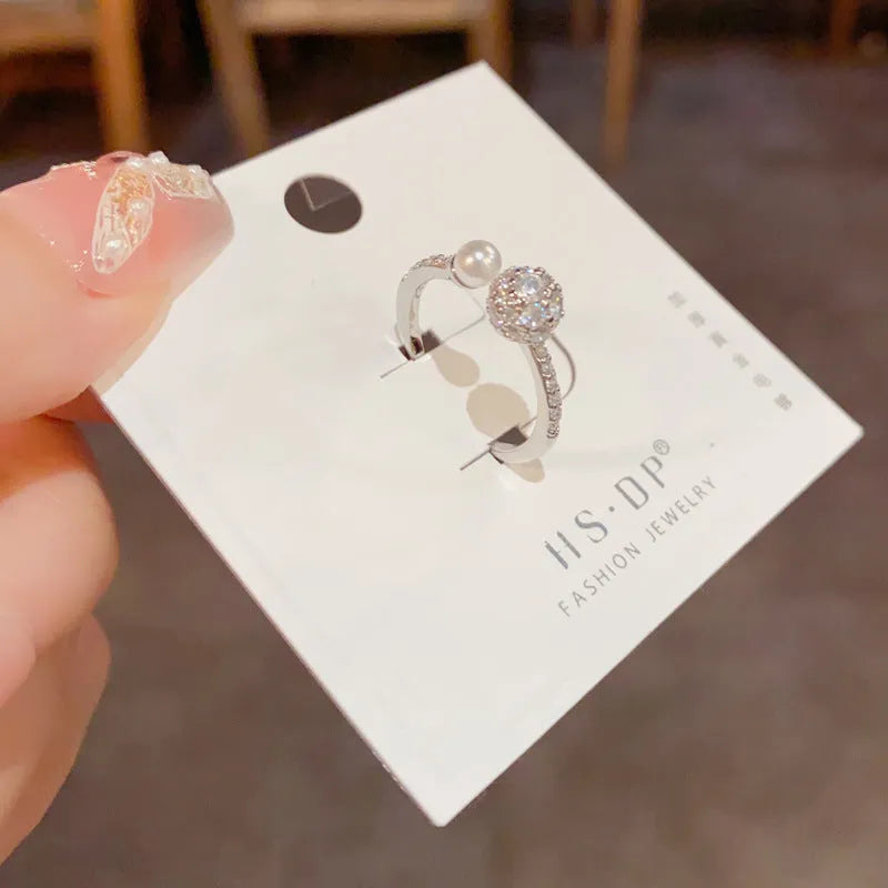 Golden open-end ring with a round zircon stone on a simple geometric band.