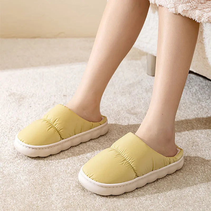 Pair of thick-soled indoor slippers in blue with a wrapped toe, low heel, and artificial plush lining.
