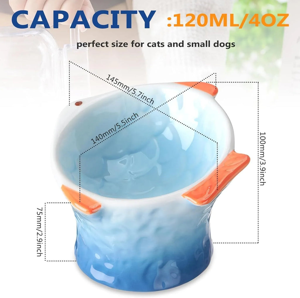 Blue fish-shaped ceramic cat feeder bowl with shallow tilt angle and non-slip base on a wooden surface.